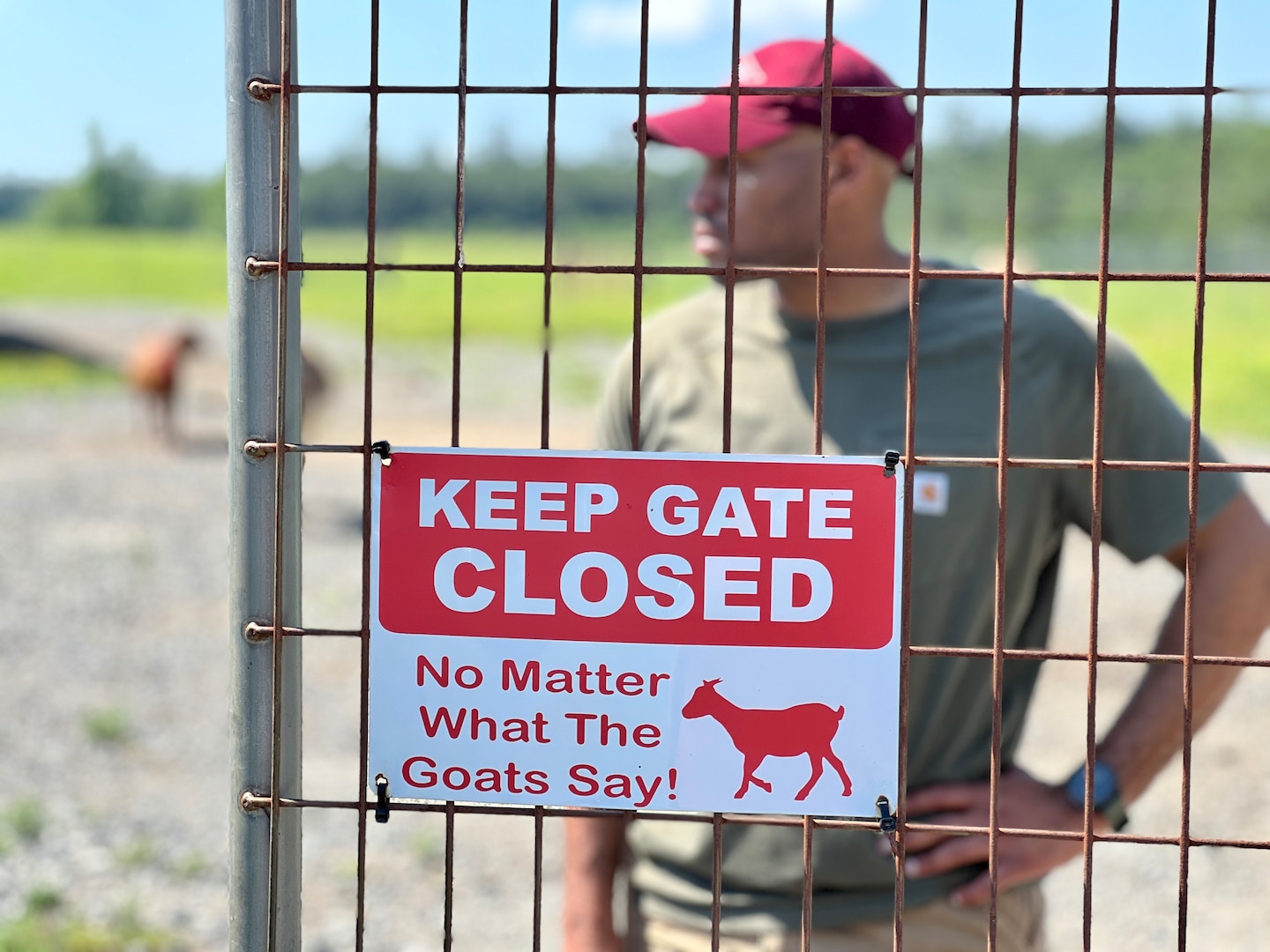 "Keep Gate Closed" sign on a fence in front of a man.