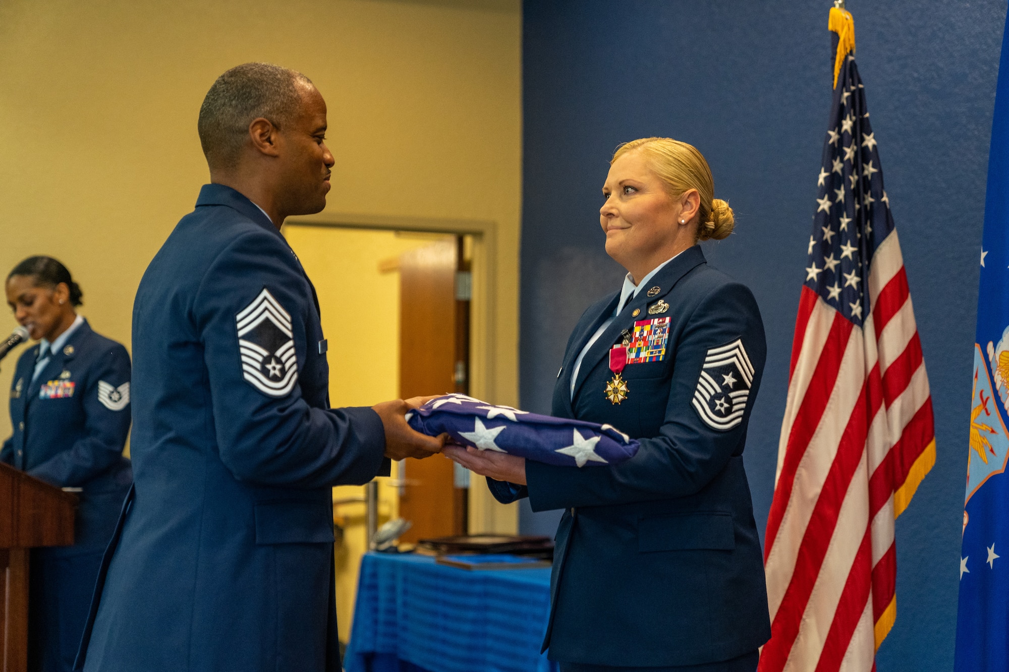 U.S. Air Force Chief Master Sgt. Marlon Jackson, Second Air Force senior enlisted leader, passes the National Colors to Chief Master Sgt. Sarah Esparza, 81st Training Wing command chief master sergeant, during her retirement ceremony at Keesler Air Force Base, Mississippi, June 1, 2023.