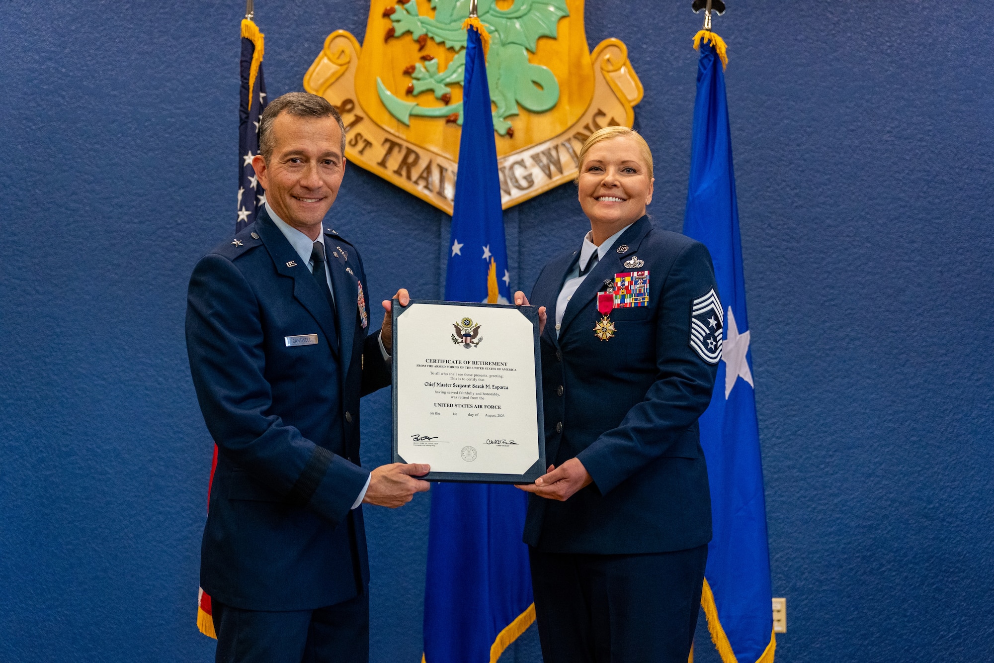 U.S. Air Force Brig. Gen. Houston Cantwell, Jeanne M. Holm Center for Oﬃcer Accessions and Citizen Development commander, and Chief Master Sgt. Sarah Esparza, 81st Training Wing command chief master sergeant, pose with her Certificate of Retirement during her retirement ceremony at Keesler Air Force Base, Mississippi, June 1, 2023.