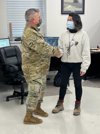 Col. Timothy Vail, U.S. Army Corps of Engineers Galveston District commander, presents Tina Le, U.S. Army Corps of Engineers, Galveston District DA Fellow, with a commander's coin for her work on soil testing, in Port Arthur, Texas, Feb. 3, 2022.