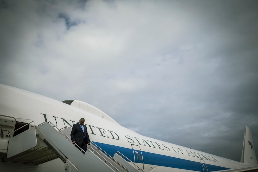 A man in a suit disembarks an airplane.