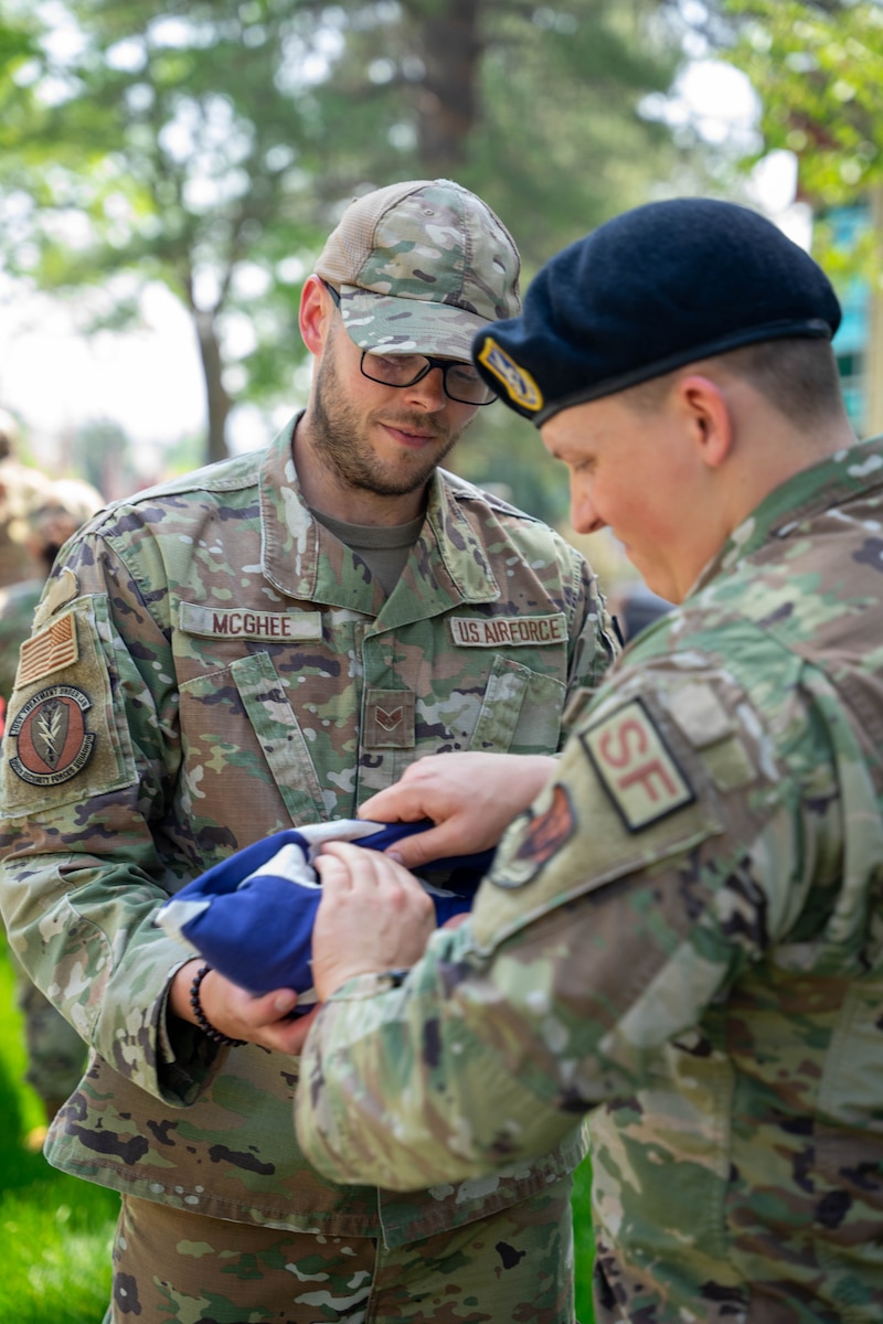 Senior Airman Rick McGhee, left, and Senior Airman Chase Lemon of the 366th Security Forces Squadron, Mountain Home Air Force Base, fold the flag at the Idaho State Veterans home, Boise, Idaho, May 20, 2023. Airmen volunteered for a car show event at the veteran’s home, assisting senior veterans with voting on their favorite car. (U.S. Air National Guard photo by Senior Airman Natalie Filzen)
