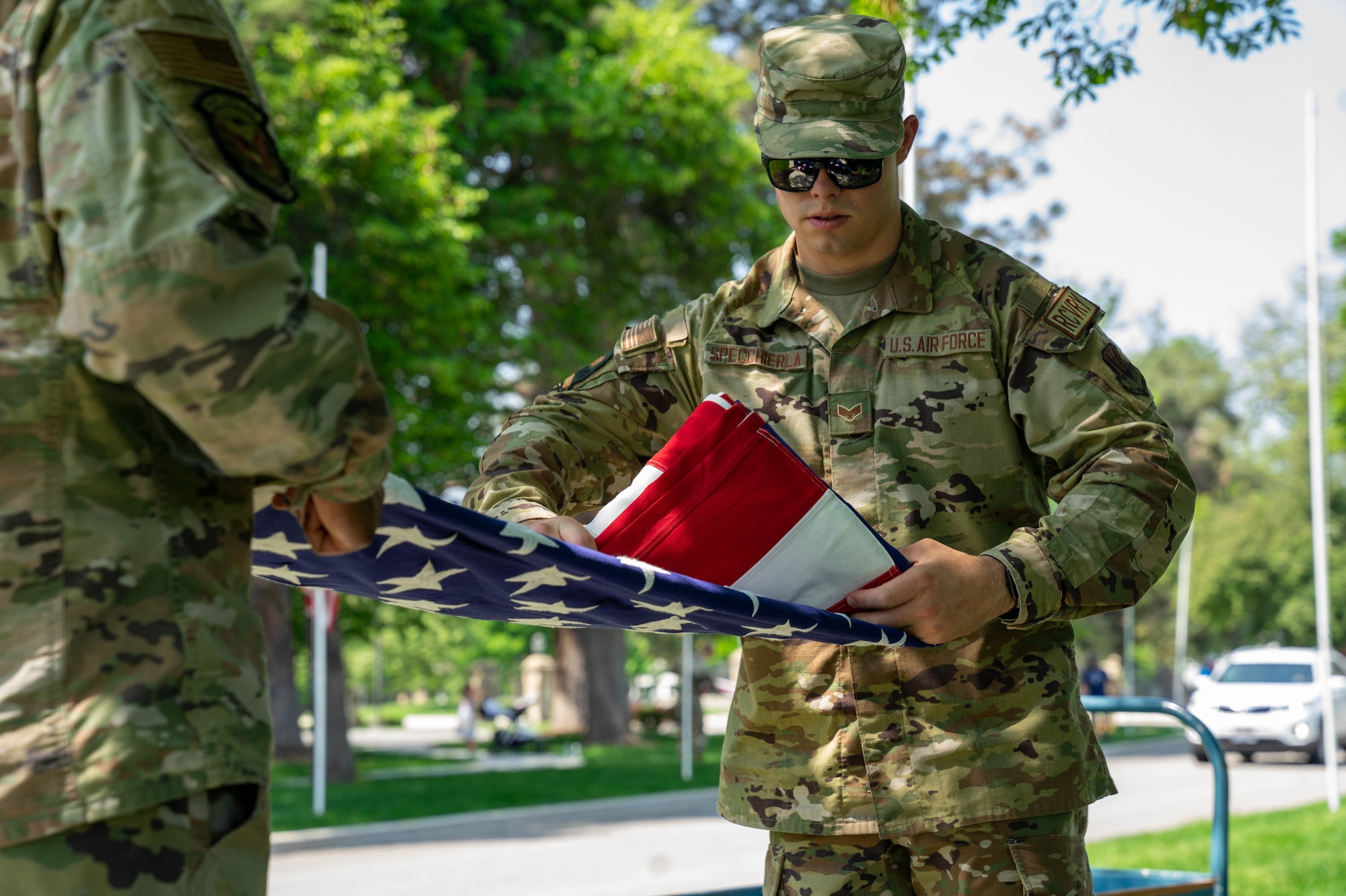 Senior Airman Marco Specchierla, 144th Fighter Wing, California Air National Guard, folds the flag at the Idaho State Veterans home, Boise, Idaho, May 20, 2023. Airmen volunteered for a car show event at the veteran’s home, assisting senior veterans with voting on their favorite car. (U.S. Air National Guard photo by Senior Airman Natalie Filzen)