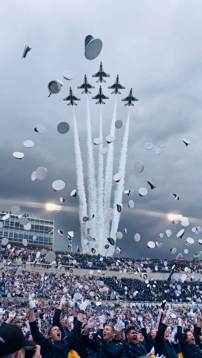  Newly-pinned 2nd Lts. from the U.S. Air Force Academy toss their caps in the air following their official dismissal from the 2023 commencement ceremony June 1, 2023. The U.S. Air Force Demonstration Squadron "Thunderbirds" ripped through the stormy sky, signaling the completion of the ceremony. (U.S. Space Force photo by Emily Peacock)