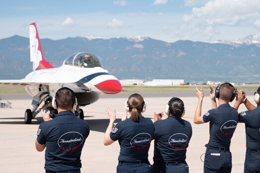  Members of the U.S. Air Force Demonstration Squadron “Thunderbirds” applaud as eight-time Olympic medalist Apolo Ohno and U.S. Air Force Thunderbirds #8 Advance Pilot Maj. Jeffrey "Simmer" Downie taxi to the runway on Peterson Space Force Base, Colorado, May 31, 2023.  Ohno received a pre-flight brief, multiple trainings, was fitted for his flight suit and helmet, and discussed what to expect with the pilot prior to departure. (U.S. Space Force photo by Airman 1st Class Justin Todd)