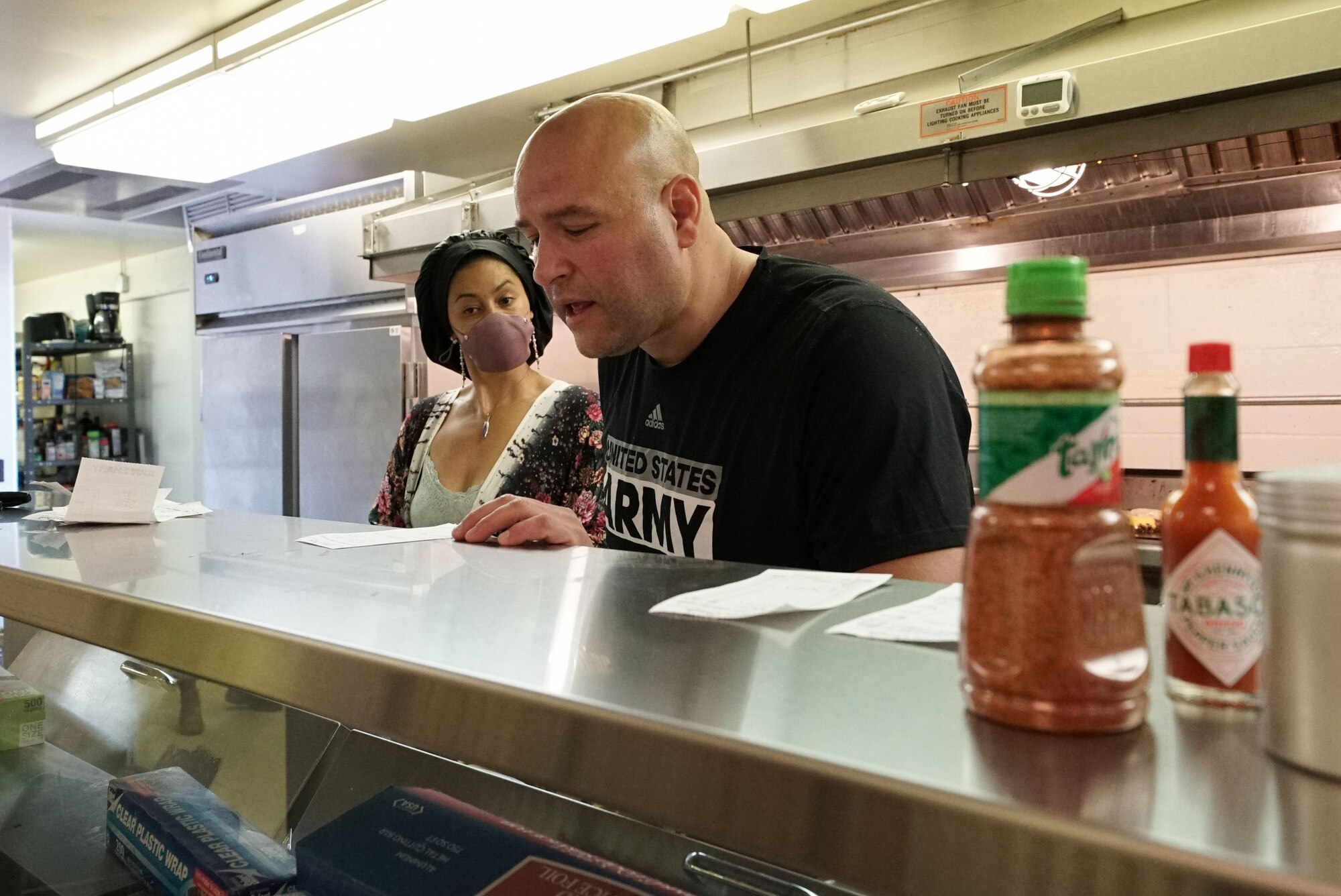 A man in a black shirt reads a white paper on a silver counter.