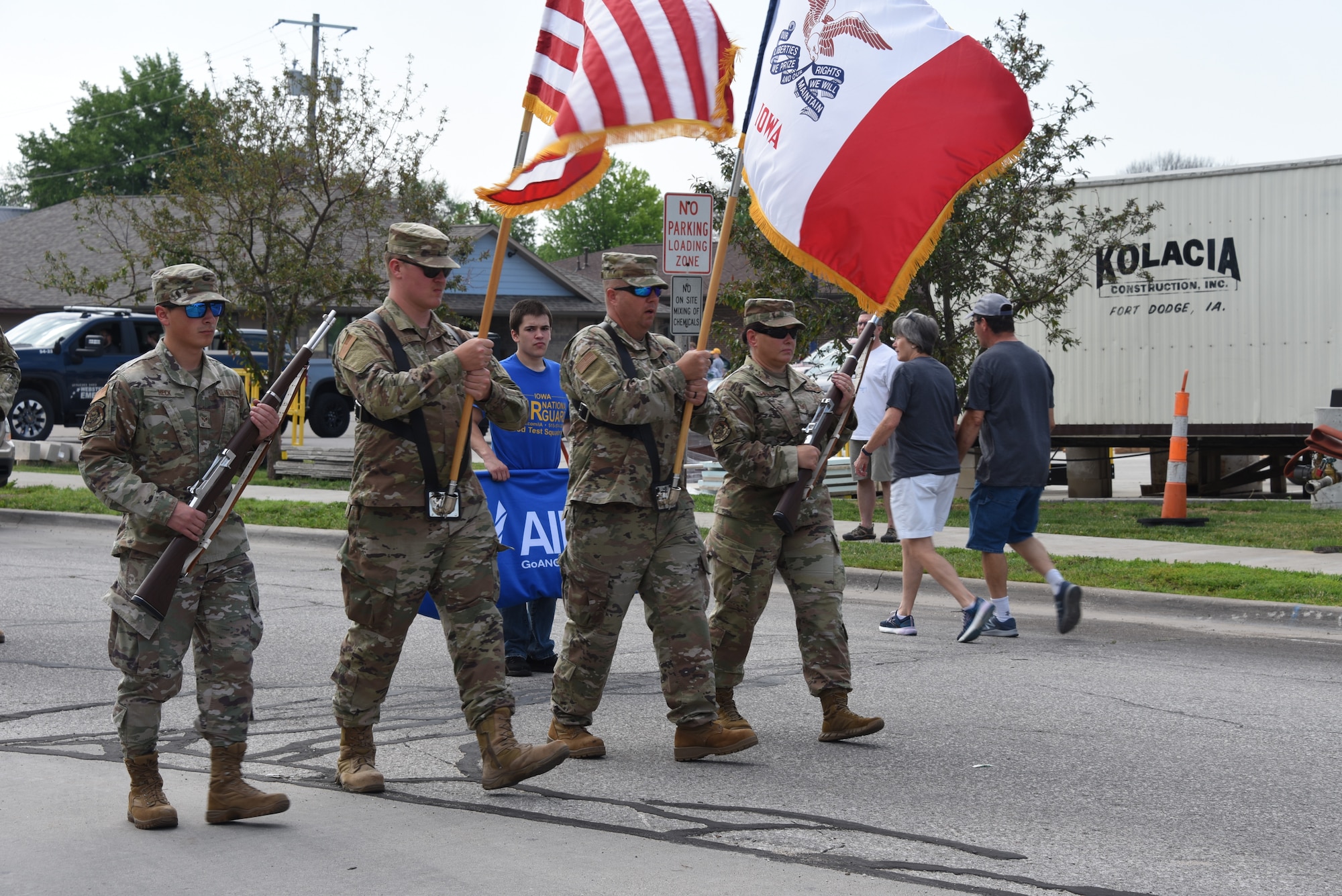 Airmen march and hold flags and ceremonial rifles.