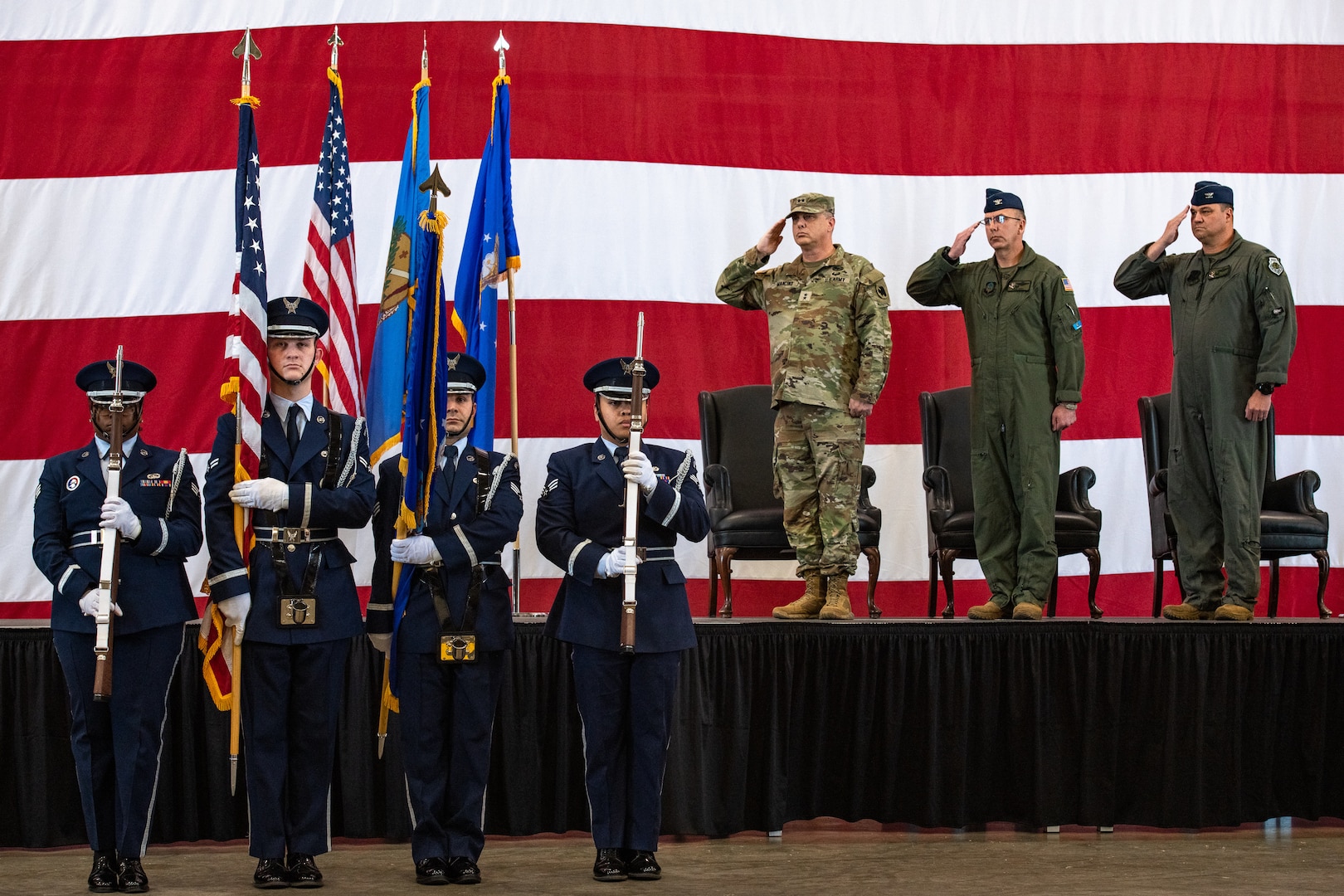 a color guard presents the american flag while military members in uniform salute
