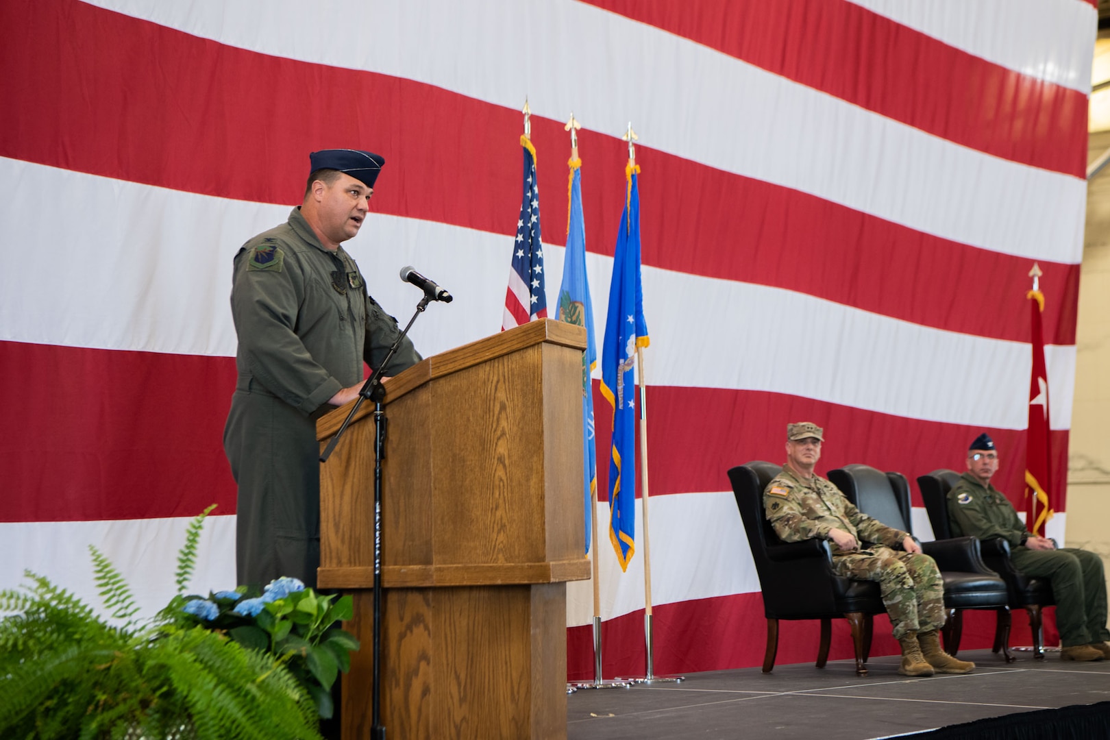 a man speaks from behind a podium that is set in front of an American flag