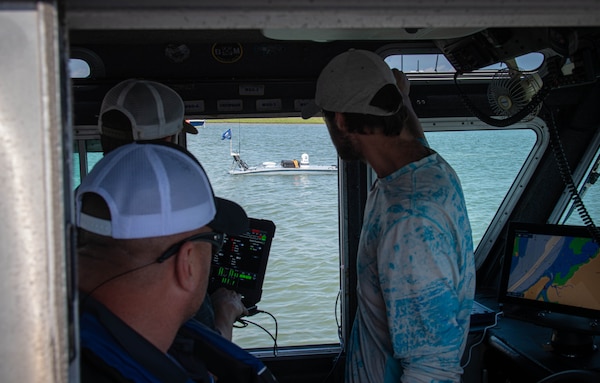 Personnel overlooking an unmanned surface vehicle through the window of the boat.