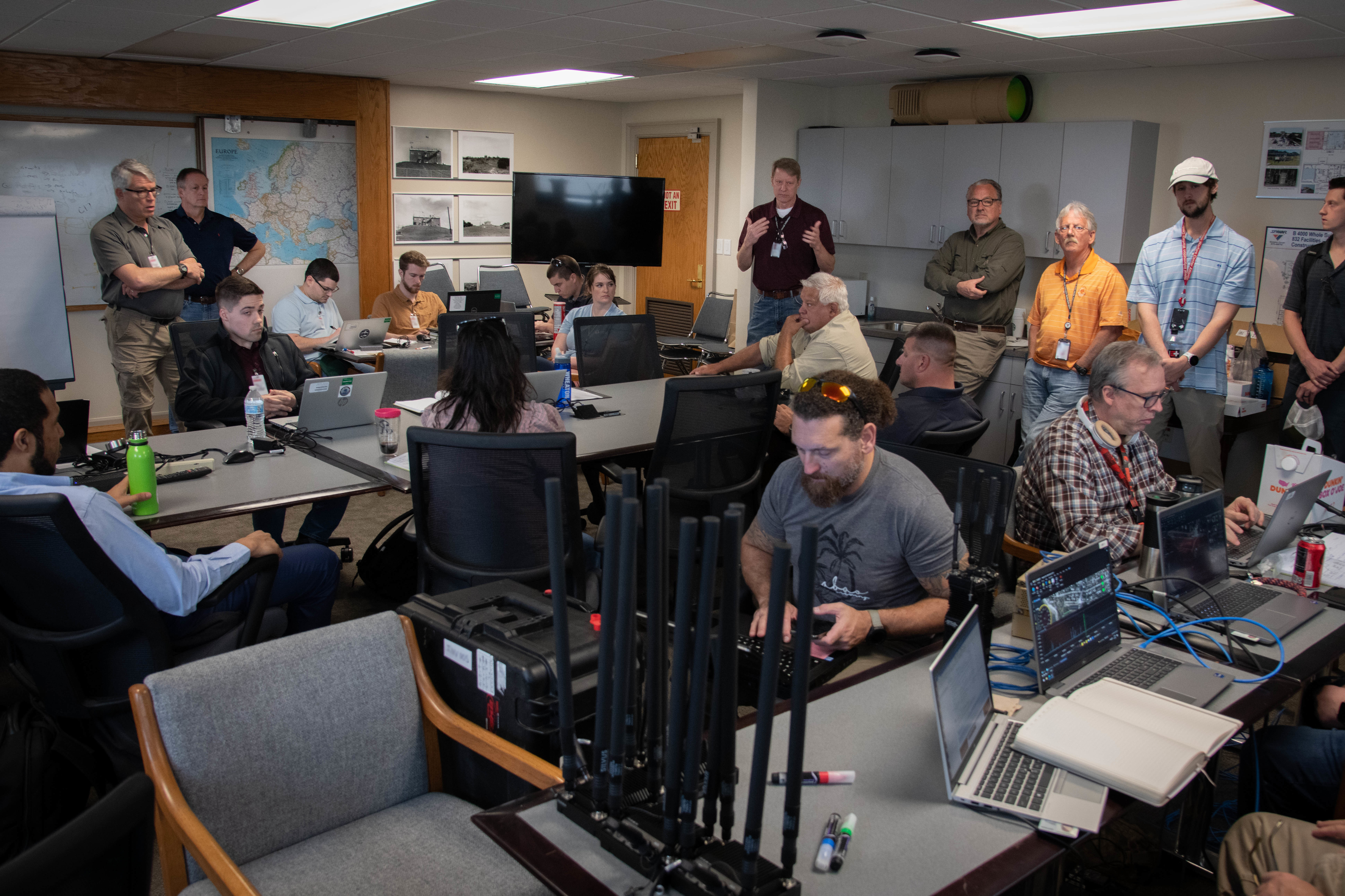 Several staff members sitting at desks in a room full of tables and radio equipment.