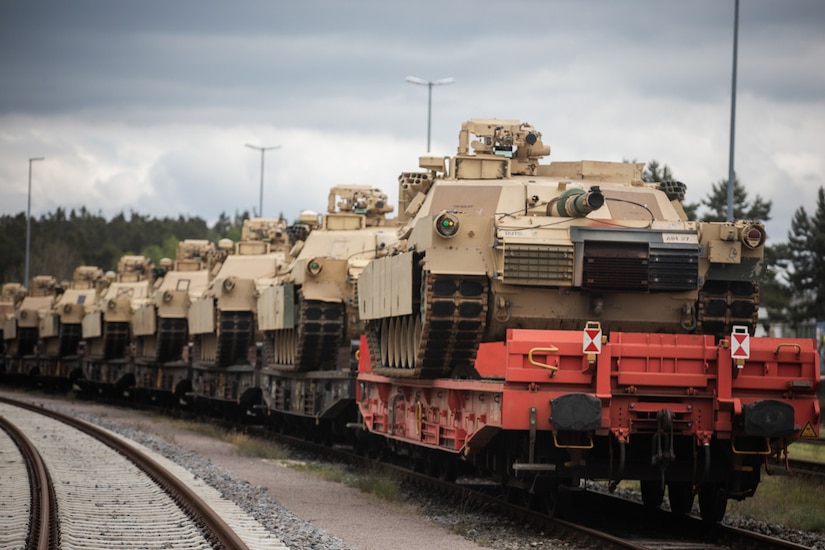 Multiple tanks sit on a train.