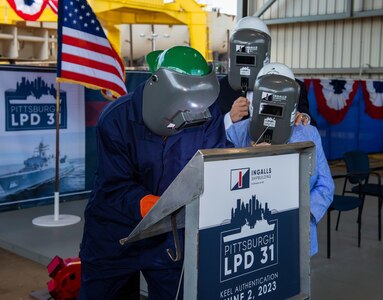 Keel Authentication ceremony of LPD 31 Pittsburgh, held at Ingalls Shipbuilding in Pascagoula, Mississippi. Pictured is welder Larry Stevens, ship sponsor Nancy Urban and her son David Urban.