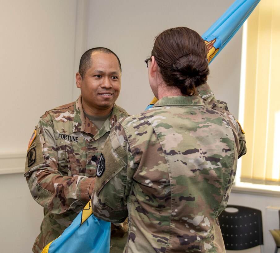 A man and a women in uniform pass the DLA flag