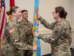 Two women in uniform pass the DLA flag