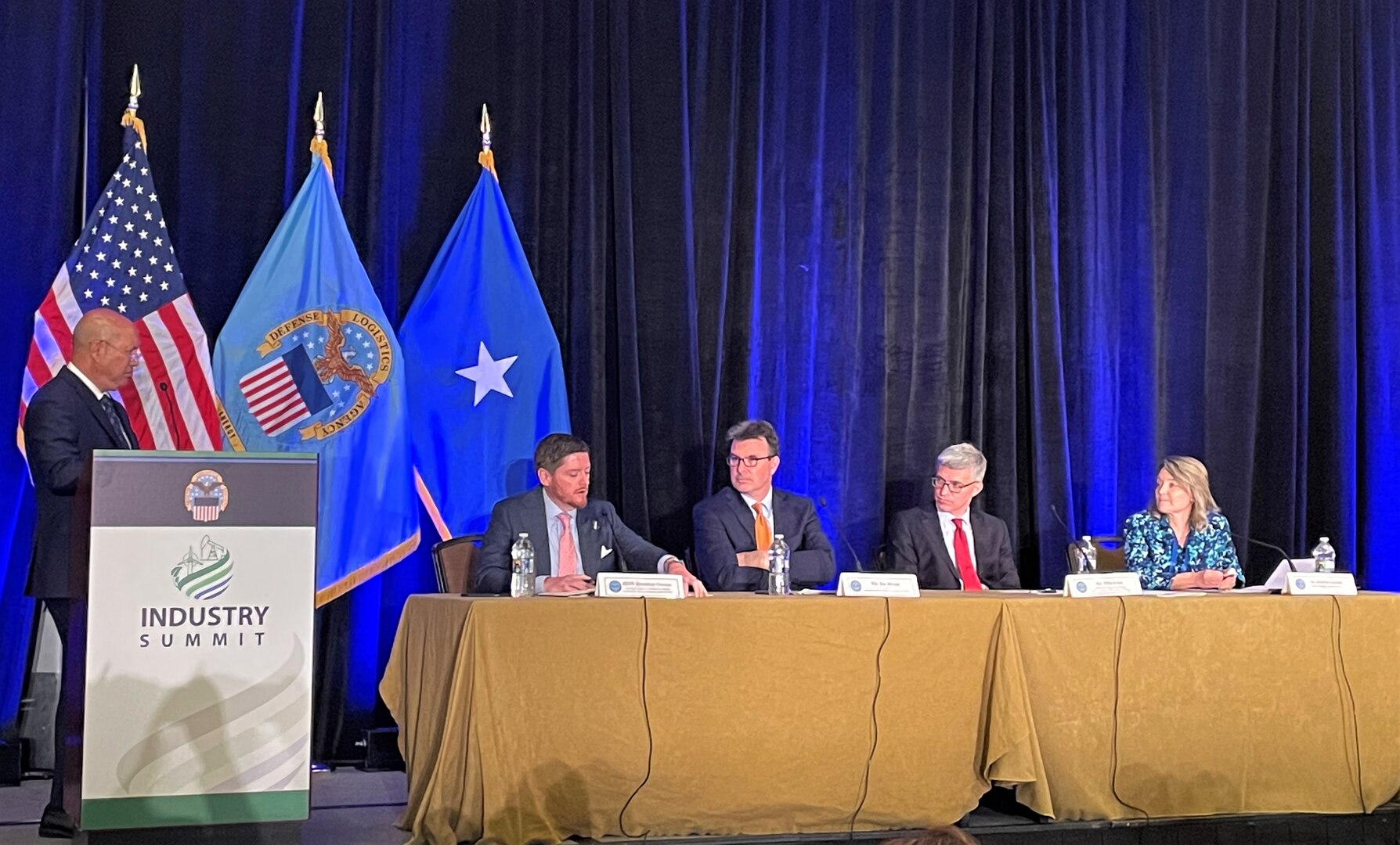 A group of people form a panel on a stage during a summit.