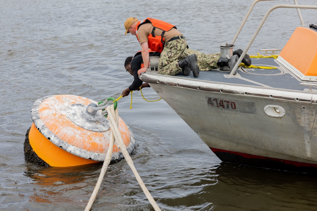 U.S. Navy Boatswain Mate 3rd Class Jaheem Jones, left, and Electrician Mate 1st Class Harrison Allen, right, both assigned to Navy Boat Docks Unit on Marine Corps Air Station (MCAS) Cherry Point, use rope to knot a boat to a buoy during a hurricane readiness exercise on MCAS Cherry Point, North Carolina, May 16, 2023. MCAS Cherry Point tested multiple scenarios during HURREX 2023, a week-long preparation exercise to test the air station’s ability and response time of various aspects to endure a destructive storm. (U.S. Marine Corps photo by Cpl. Jade Farrington)