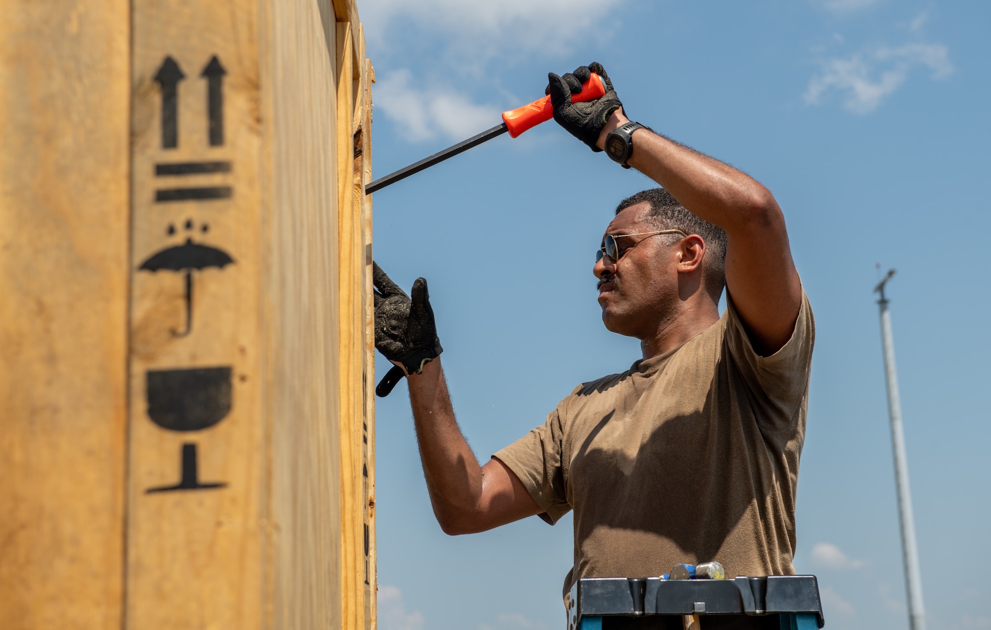 Airmen removes side paneling of a crate