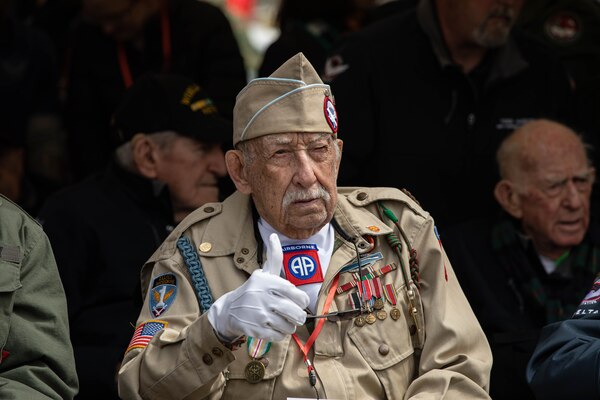 A veteran wearing white gloves gives a thumbs up sign.