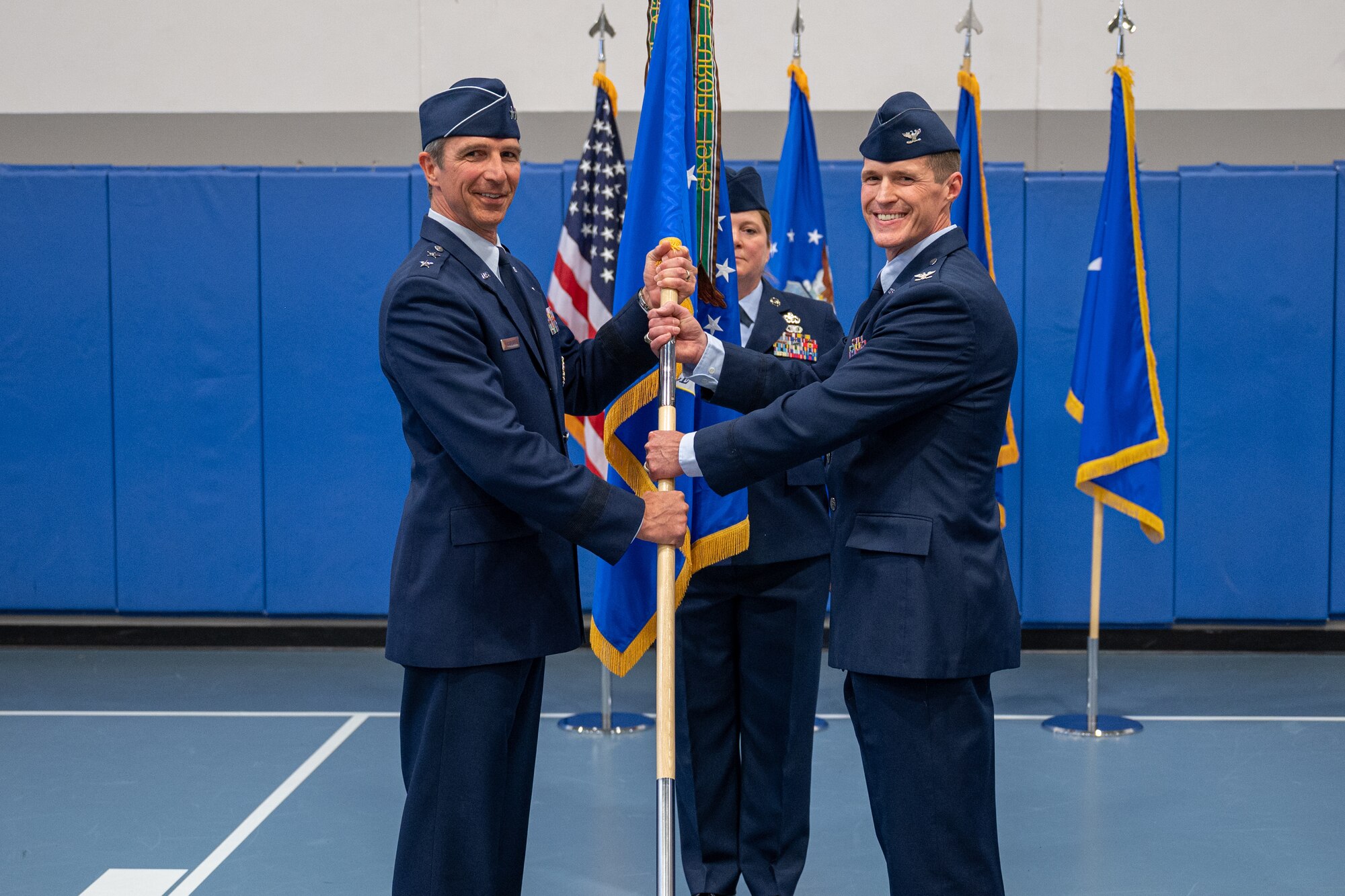 two individuals holding a flag, and posing for a photo.
