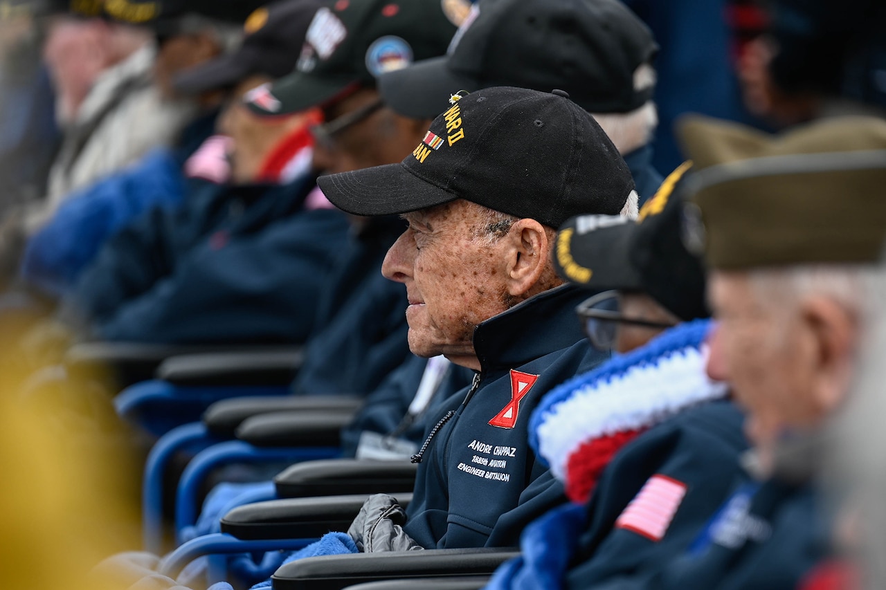 WWII veterans are seated during a D-Day ceremony.