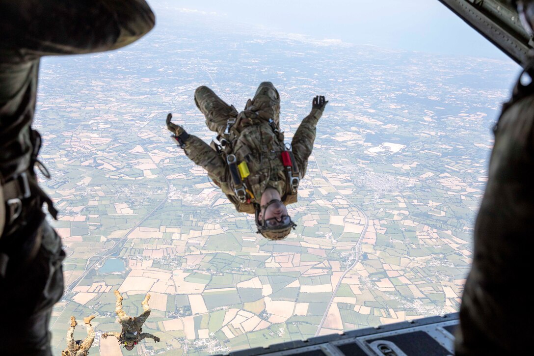 Military members jump from an aircraft.