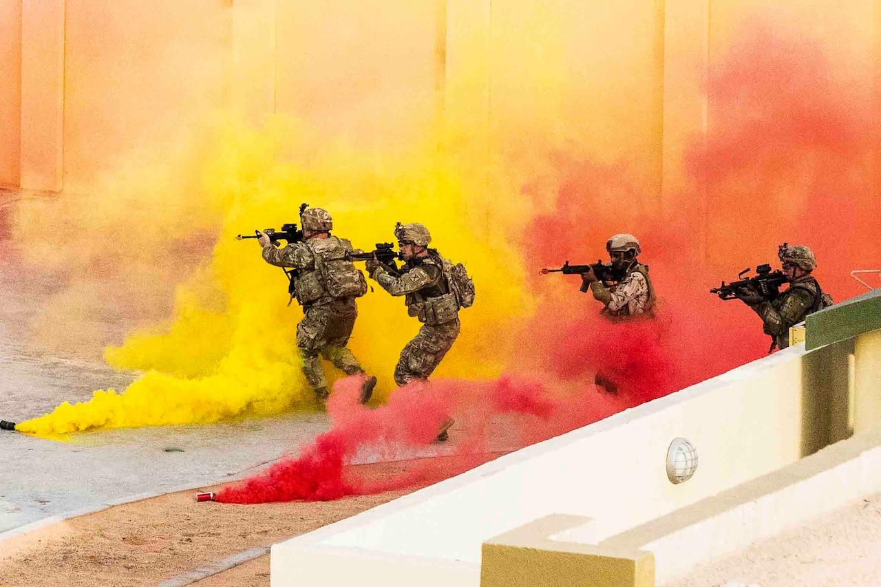 Soldiers move through yellow and red smoke with their weapons drawn.