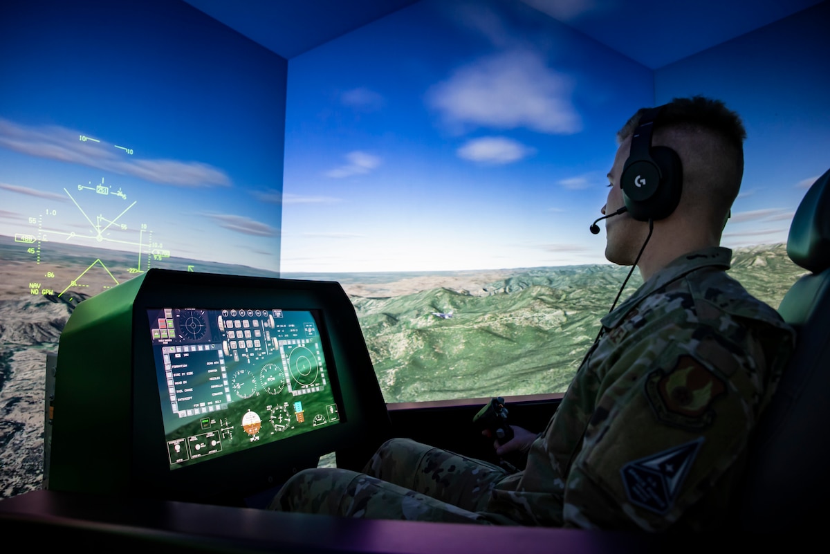 2nd Lt. Ryan Collins demonstrates an automatic fly up maneuver generated by the Automatic Ground Collision Avoidance System, or Auto GCAS, in a research flight simulator, Dec. 6, 2022, at the Air Force Research Laboratory, or AFRL, Aerospace Systems Directorate at Wright-Patterson Air Force Base, Ohio. Auto GCAS is a software update developed by AFRL, Lockheed Martin and NASA that prevents an aircraft from impacting the ground by automatically pulling the aircraft up before an accident can occur. Kerianne Hobbs, safe autonomy and space lead with the Autonomy Capability Team, or ACT3, for the Sensors Directorate at AFRL, was the lead author of a 38-page spread in the Institute of Electrical and Electronics Engineers Control Systems Magazine, titled Runtime assurance for safety-critical systems: An introduction to safety filtering approaches for complex control systems, for her extensive research in runtime assurance. (U.S. Air Force photo / Richard Eldridge)