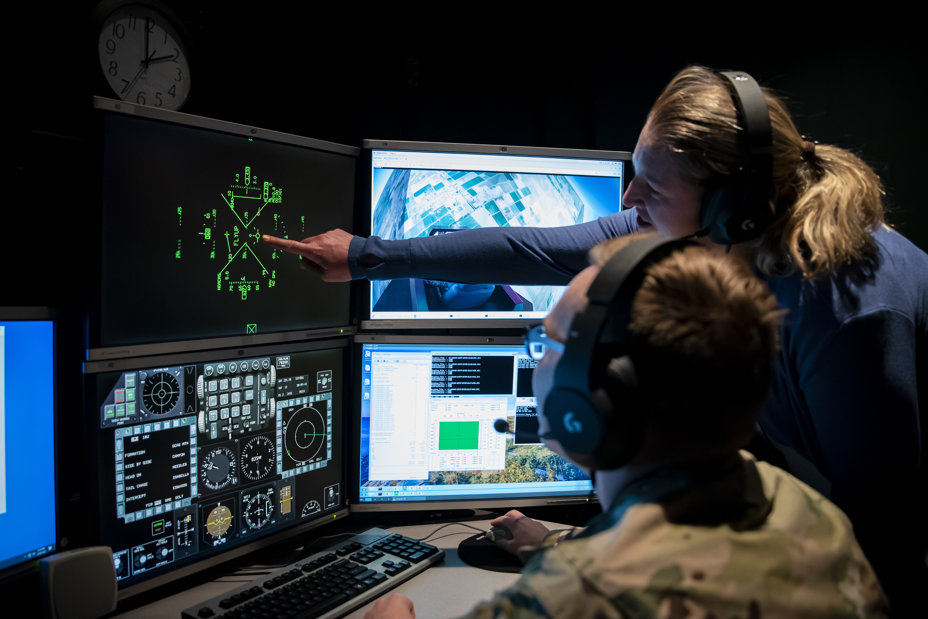 Air Force Research Laboratory, or AFRL, Controls Engineer Capt. Christian Potts, left, and Program Manager Amy Burns, right, watch from the simulation control room at AFRL’s Aerospace Systems Directorate while 2nd Lt. Ryan Collins demonstrates automatic fly up maneuvers in a virtual flight simulator generated by the Automatic Ground Collision Avoidance System, or Auto GCAS, Dec. 6, 2022, at Wright-Patterson Air Force Base, Ohio. Auto GCAS is a software update developed by AFRL, Lockheed Martin and NASA that prevents an aircraft from impacting the ground by automatically pulling the aircraft up before an accident can occur. Kerianne Hobbs, safe autonomy and space lead with the Autonomy Capability Team, or ACT3, for the Sensors Directorate at AFRL, was the lead author of a 38-page spread in the Institute of Electrical and Electronics Engineers Control Systems Magazine, titled Runtime assurance for safety-critical systems: An introduction to safety filtering approaches for complex control systems, for her extensive research in runtime assurance. (U.S. Air Force photo / Richard Eldridge)