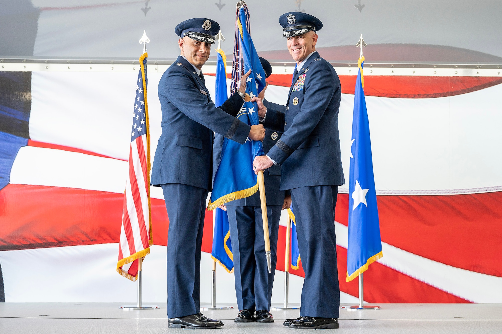 U.S. Air Force Maj. Gen. Clark Quinn, right, 19th AF commander, receives the unit guidon from Lt. Gen. Brian Robinson, left, commander of Air Education and Training Command, during the 19th AF assumption of command ceremony