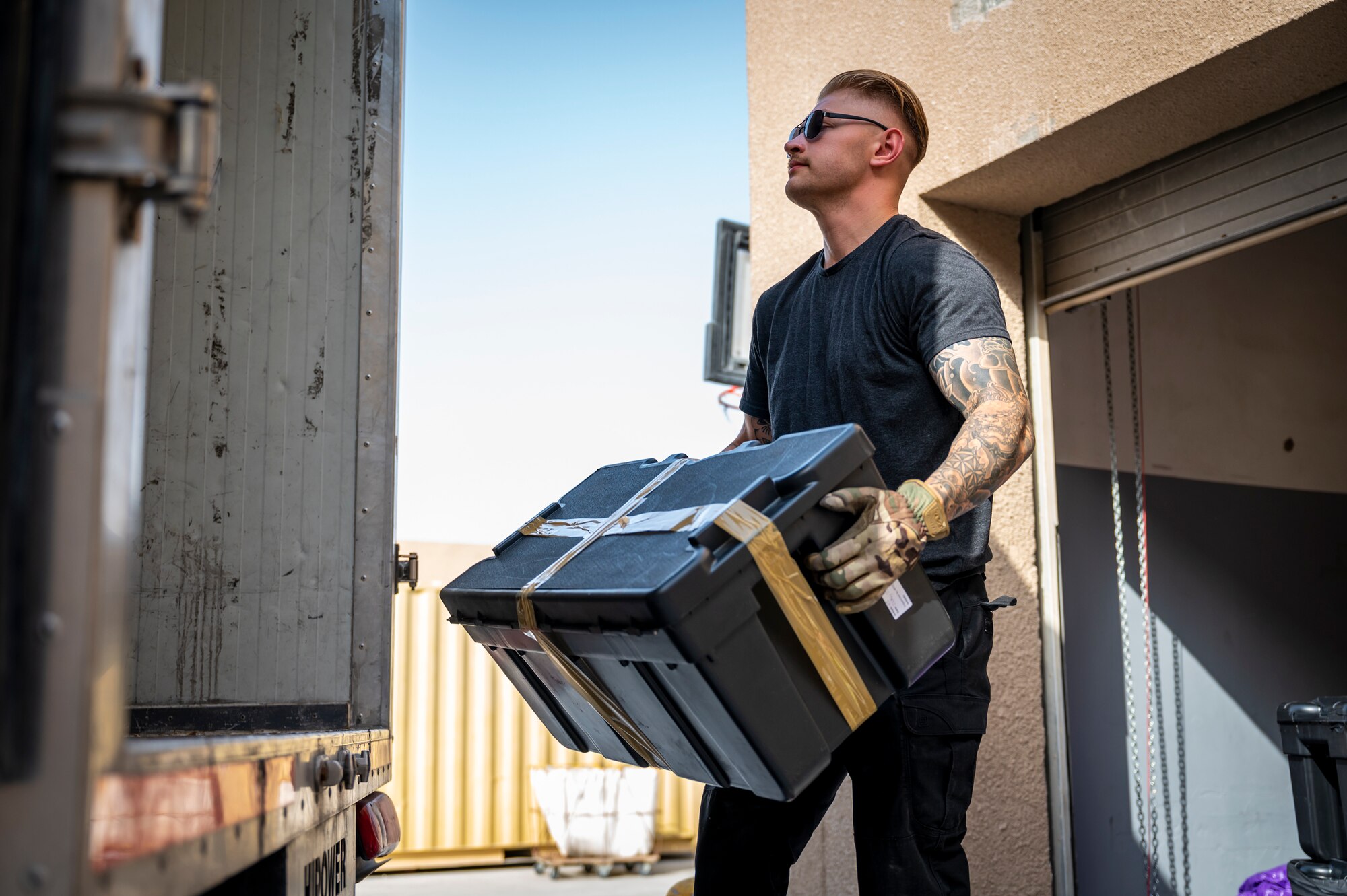 A military members holds a package at the end of the truck for loading.