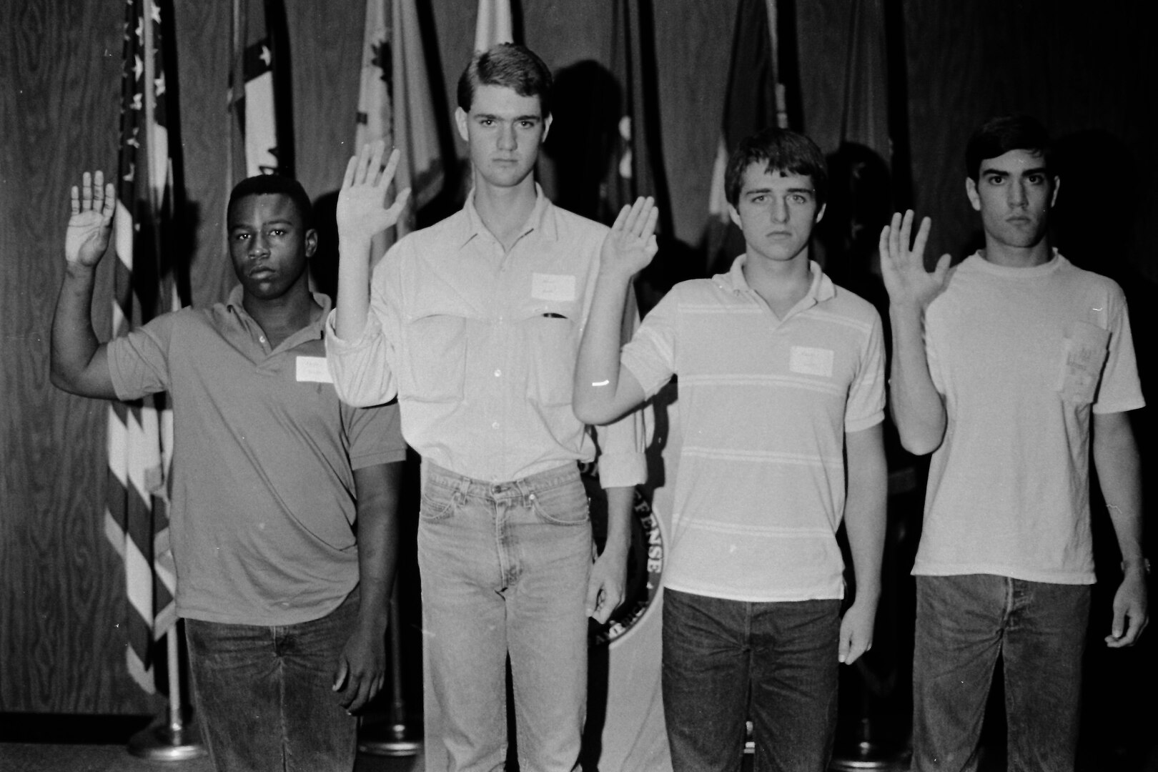 Four young men stand with their right hands raised during an enlistment.