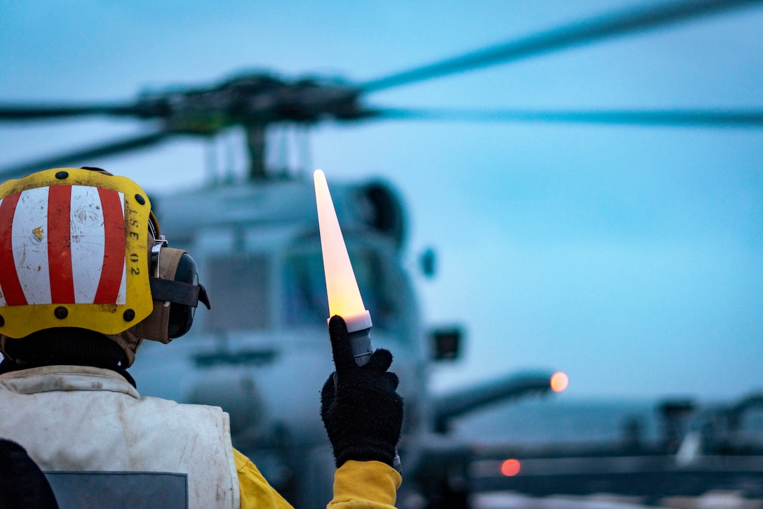 A sailor signals a helicopter during a training exercise.