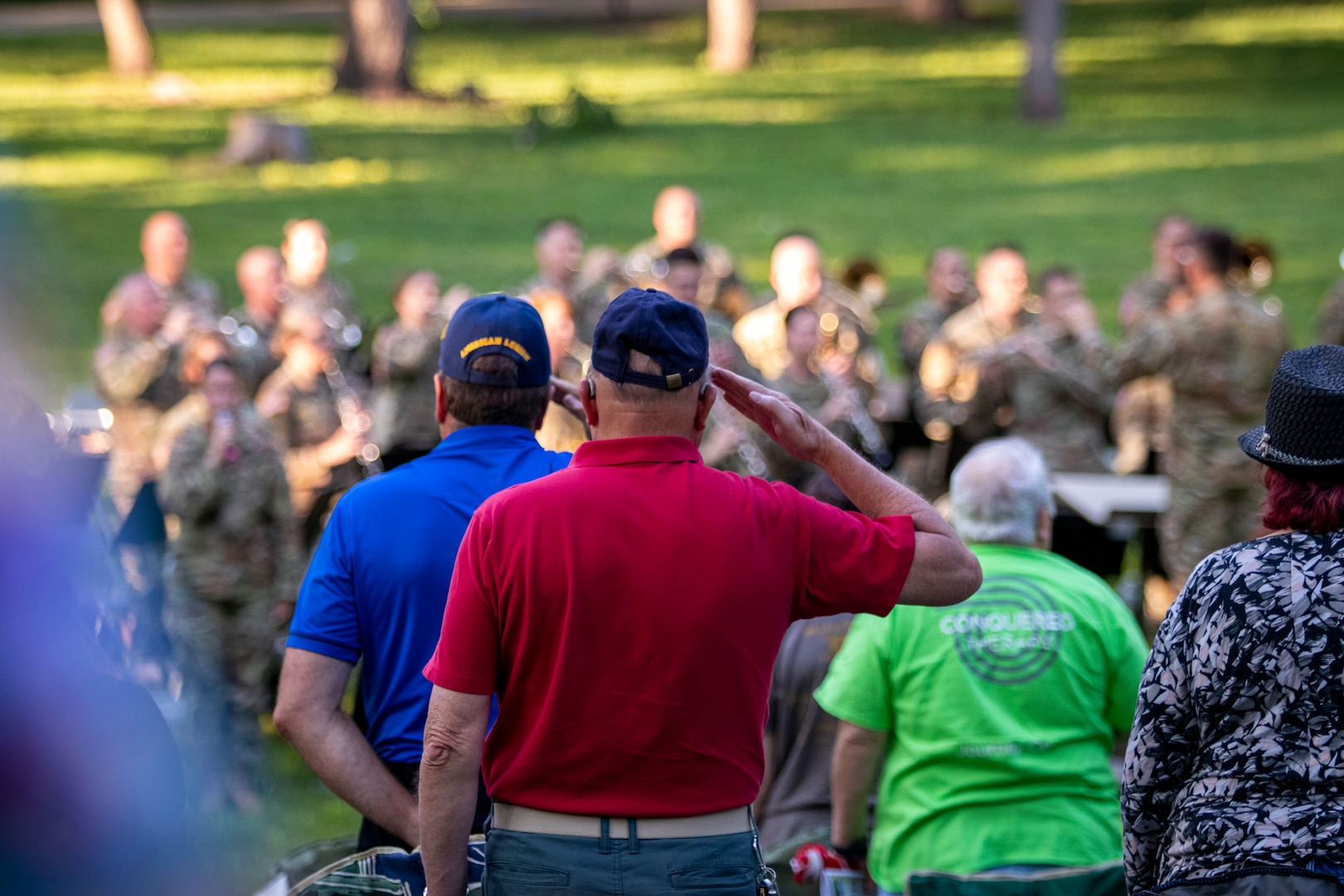 Veterans salute during the National Anthem performed by the Nebraska Army National Guard's 43rd Army Band as they celebrate 75 years of service with an anniversary concert, June 3, 2023, at the Wildewood Park in Ralston, Nebraska.