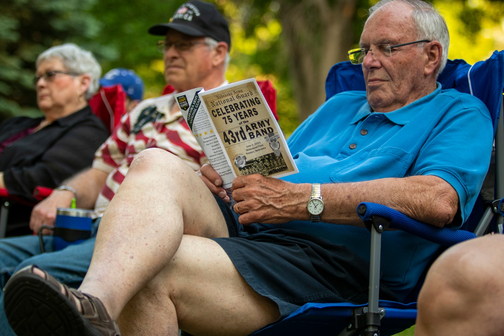 A concert attendee reads a program for the Nebraska Army National Guard's 43rd Army Band as they celebrate 75 years of service with an anniversary concert, June 3, 2023, at the Wildewood Park in Ralston, Nebraska.