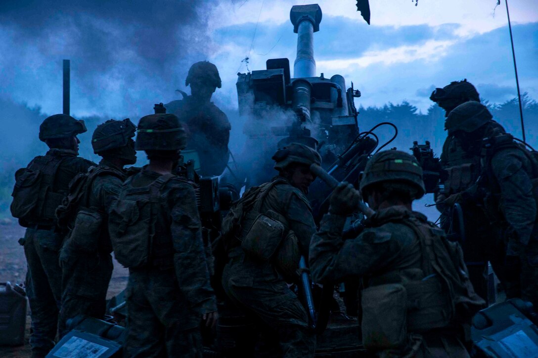 Marines load and fire a large weapon.
