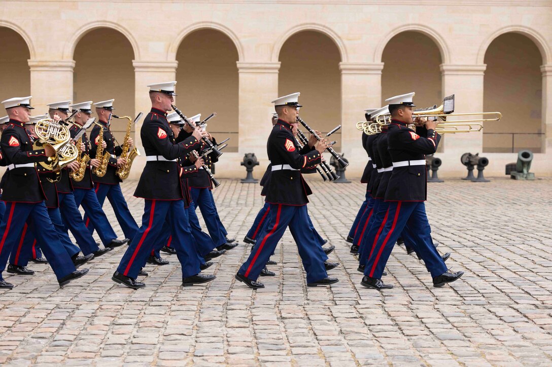 Marines march in formation while playing instruments.