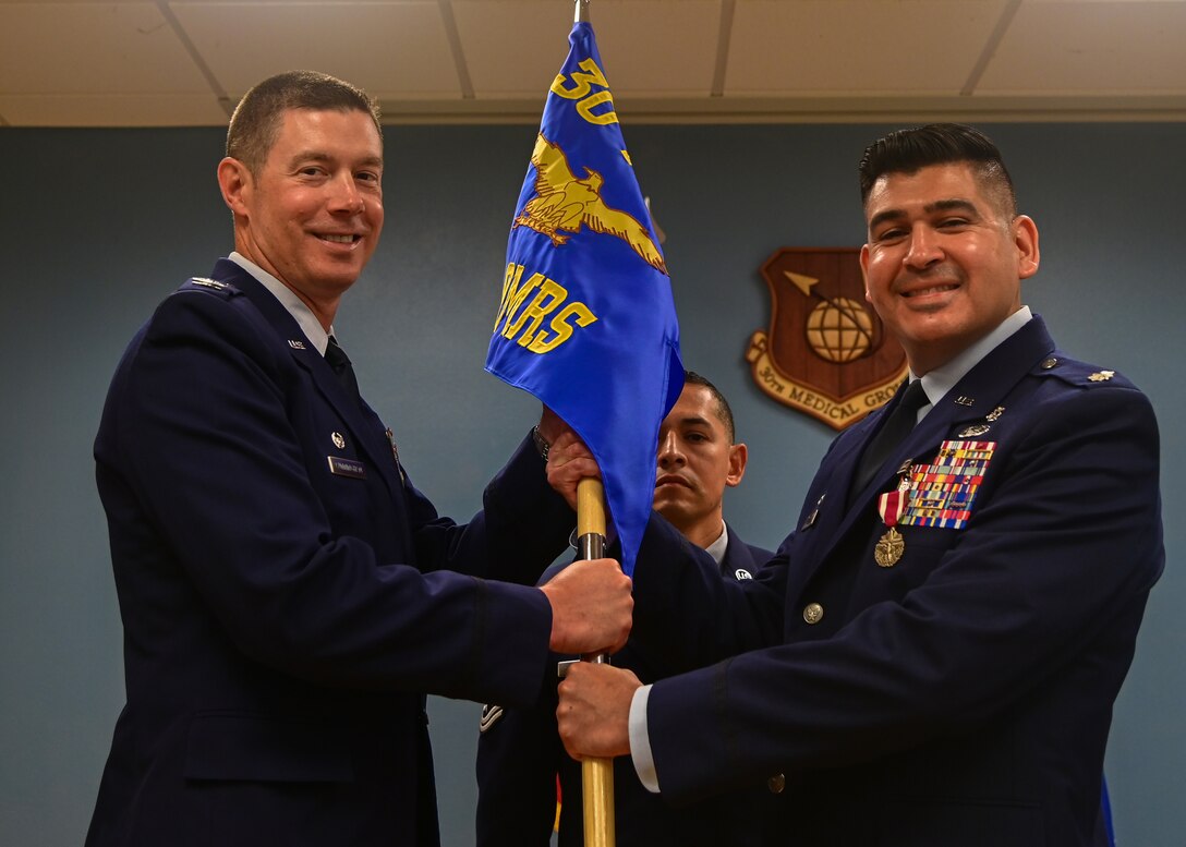 U.S. Air Force Lt. Col. Eduardo Cervantes, outgoing 30th Operational Medical Readiness Squadron commander, passes the 30th OMRS flag to U.S. Air Force Col. Brent Cunningham, 30th Medical Group commander, during a change of command ceremony on Vandenberg Space Force Base, Calif., June 6, 2023. Lt. Col. Marcus Boone will take Lt. Col. Cervantes' place as the 30th OMRS commander. (U.S. Space Force photo by Airman 1st Class Ryan Quijas)