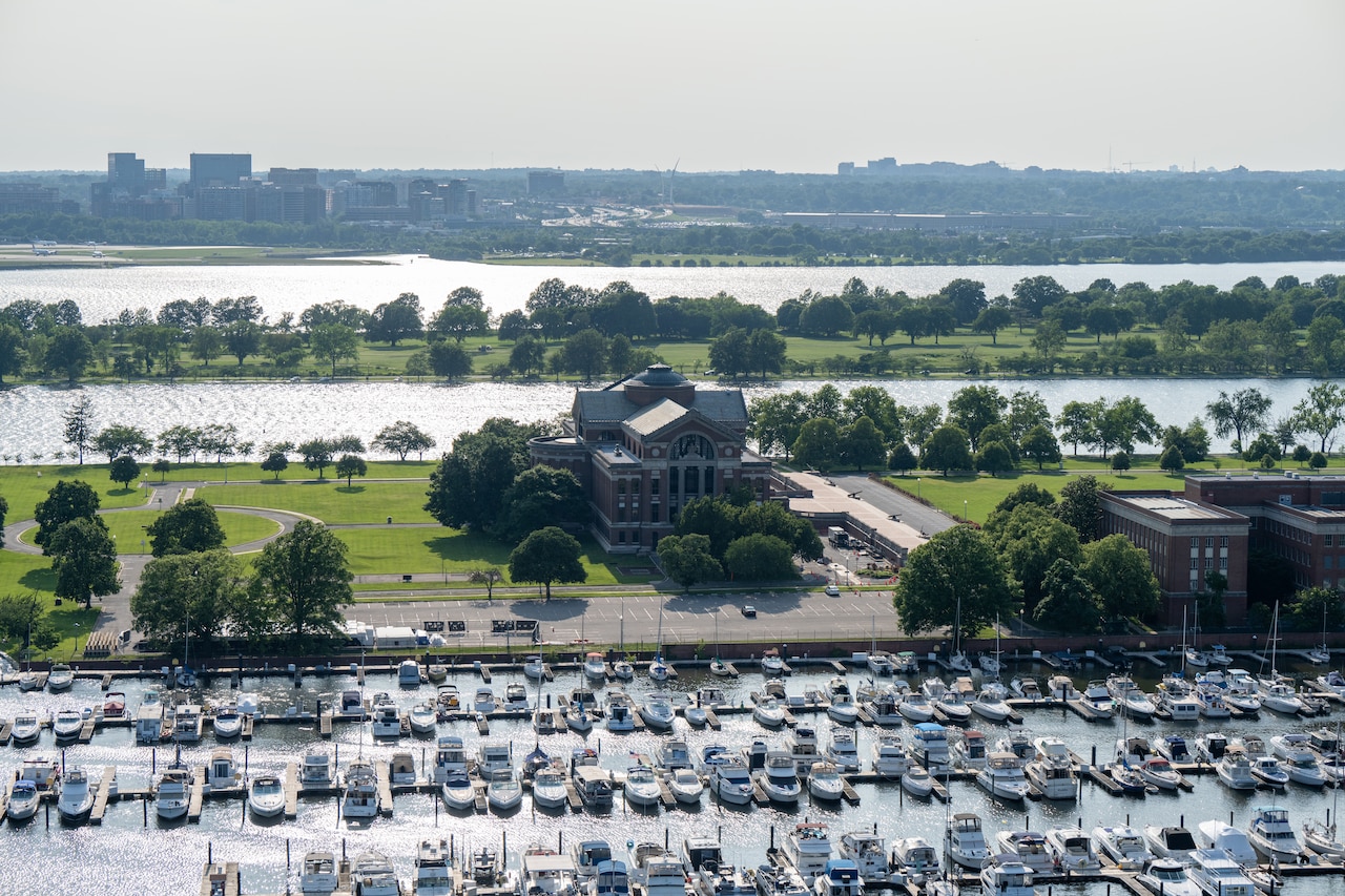 An aerial view of two large buildings and several boat docks with boats in them.