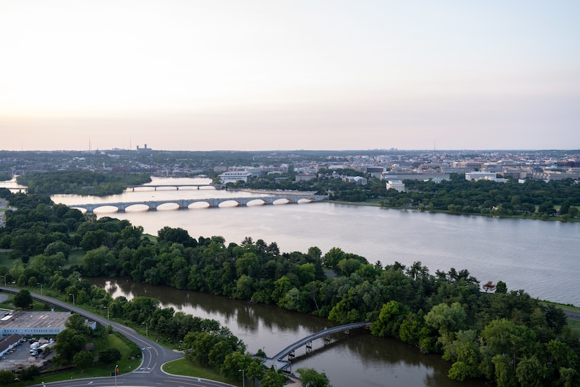 An aerial view shows a tree-lined river with three bridges and a side waterway.