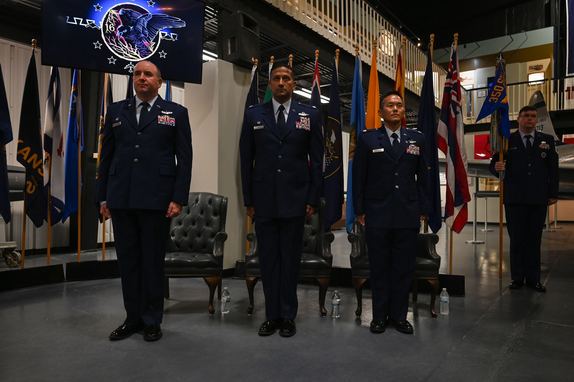 U.S. Air Force Col. Robert P. Cocke, 350th Spectrum Warfare Group commander, left, Lt. Col. Ajay K. Giri, 16th Electronic Warfare Squadron (EWS) outgoing commander, center, and Lt. Col. Chad R. Nishizuka, 16th EWS incoming commander, right stand at attention during a change of command at Eglin Air Force Base, June 6, 2023. The mission of the 16th EWS is to develop, test, validate, and field electromagnetic warfare capabilities for the warfighter. (U.S. Air Force photo by Staff Sgt. Ericka A. Woolever)