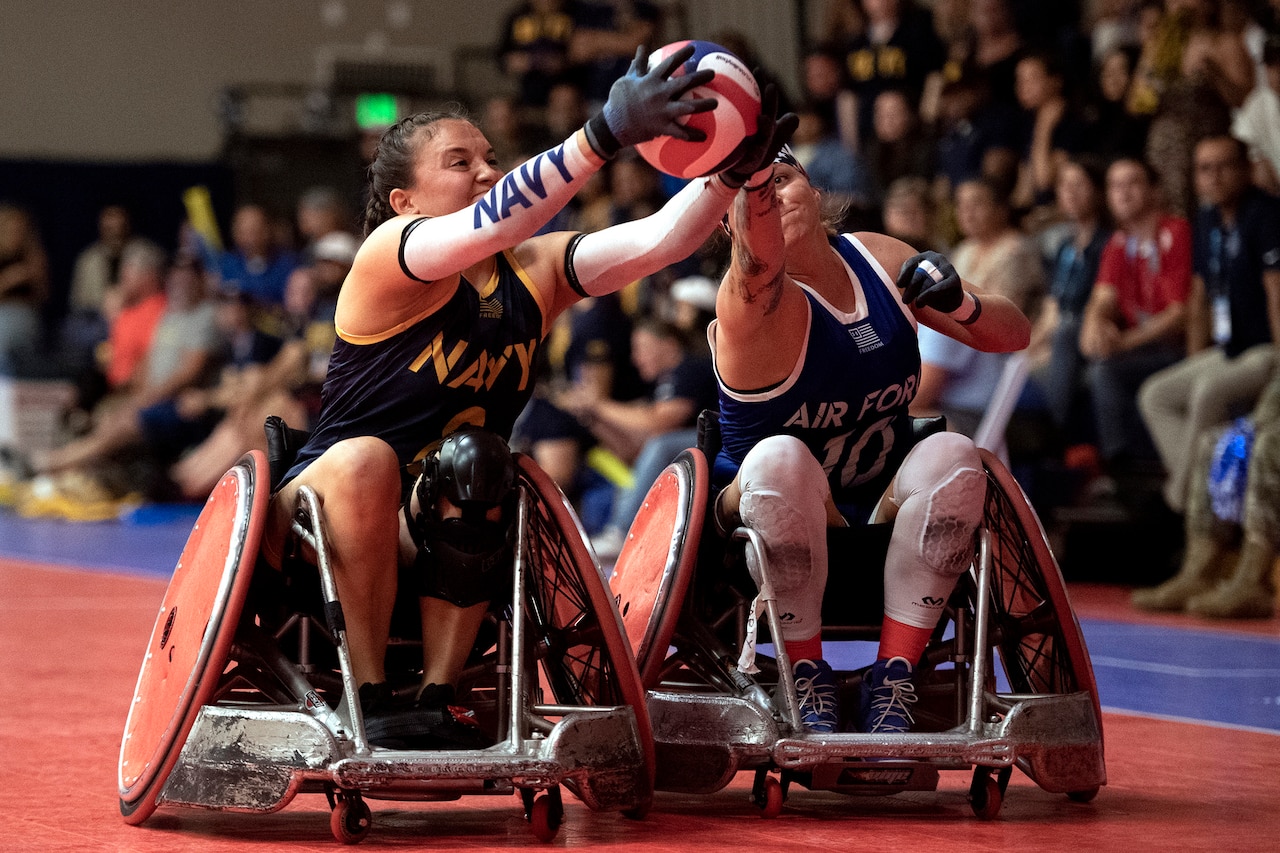 A sailor and an airman battle for a ball while in wheelchairs.