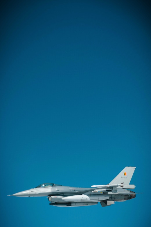 An aircraft is seen in side profile against a solid blue sky.