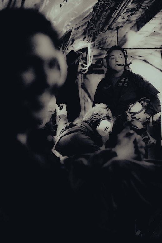 Several airmen and civilians are shown wearing headphones aboard an aircraft.
