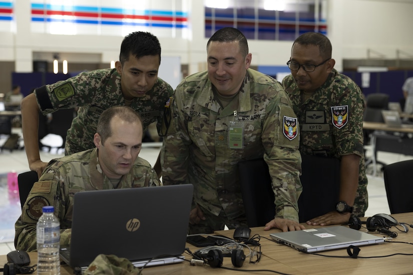 Service members look over a laptop.