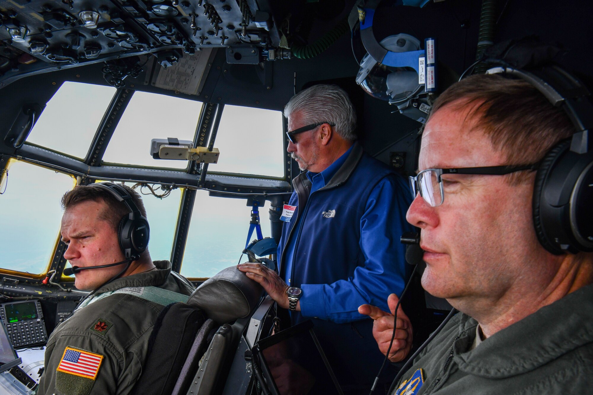 Chief Master Sgt. Scott Young, a flight engineer, and Maj. Bret Larson, a pilot, both assigned to the 757th Airlift Squadron, talk with a participant in the 910th Airlift Wing’s civic leader tour on the fight deck of a C-130H Hercules aircraft while flying to Dobbins Air Reserve Base, Georgia, May 11, 2023.