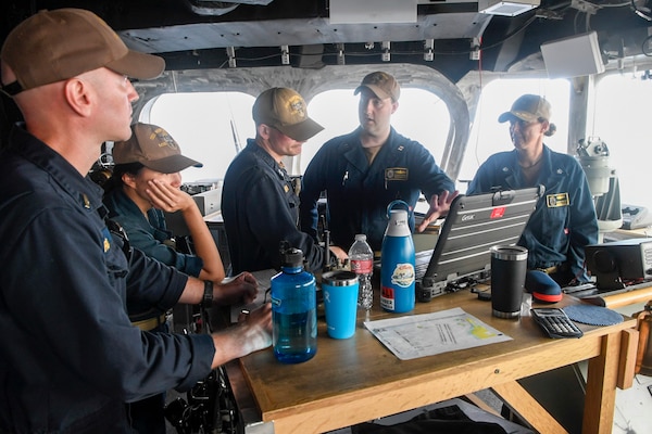 Cmdr. Collen Moore, commanding officer of the Independence-variant littoral combat ship USS Manchester (LCS 14), and assigned Sailors discuss the anchor's movement from the bridge.