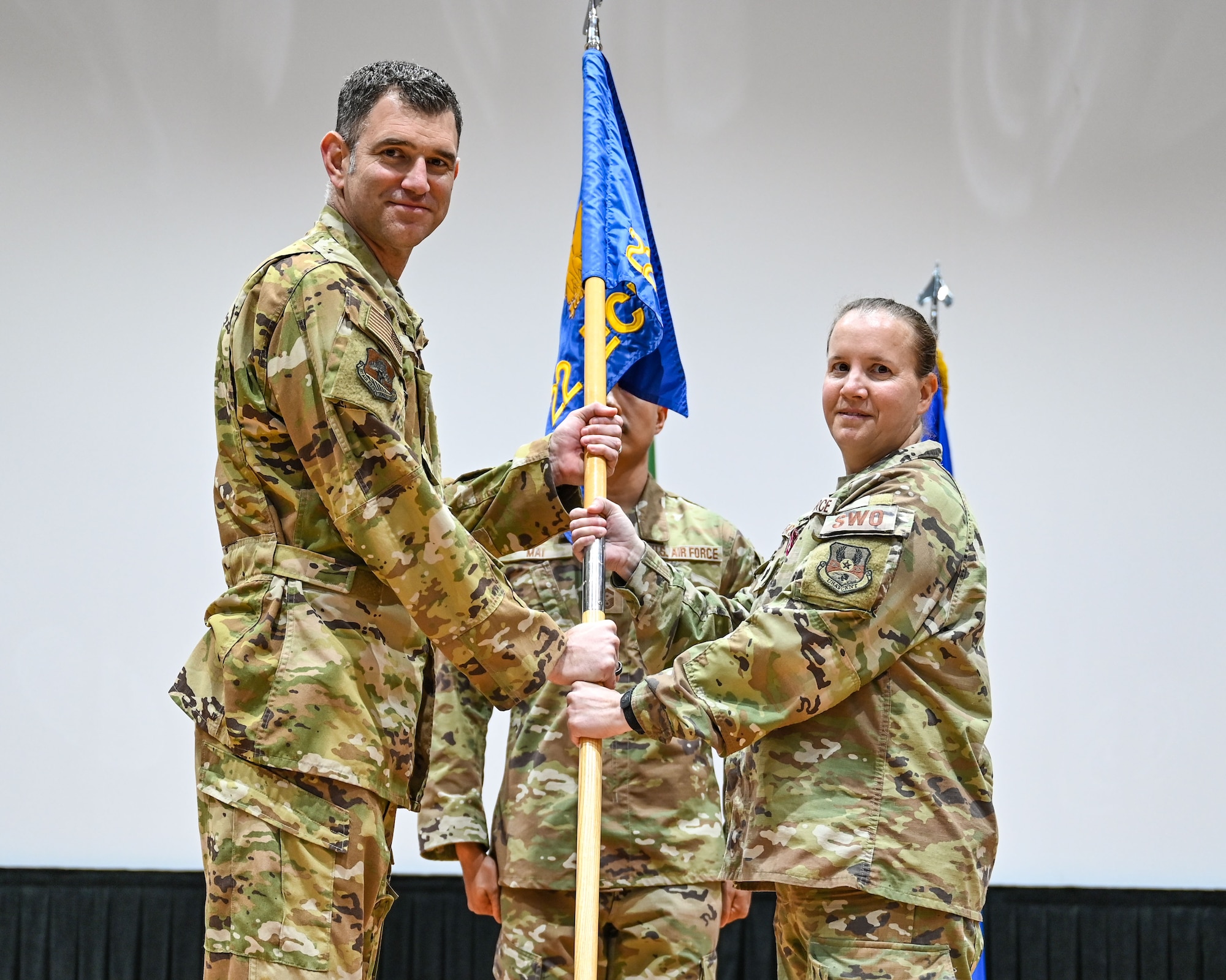 Lt. Col. Mindy Pearson, outgoing 22nd Expeditionary Combat Weather Squadron commander, passes the guidon to Col. Jeremy Ponn, 387th Air Expeditionary Group commander, during a change of command ceremony at Ali Al Salem Air Base, Kuwait, June 7, 2023. Pearson passed the guidon back to Ponn as a symbol of relinquishing command of the unit. (U.S. Air Force photo by Staff Sgt. Breanna Diaz)