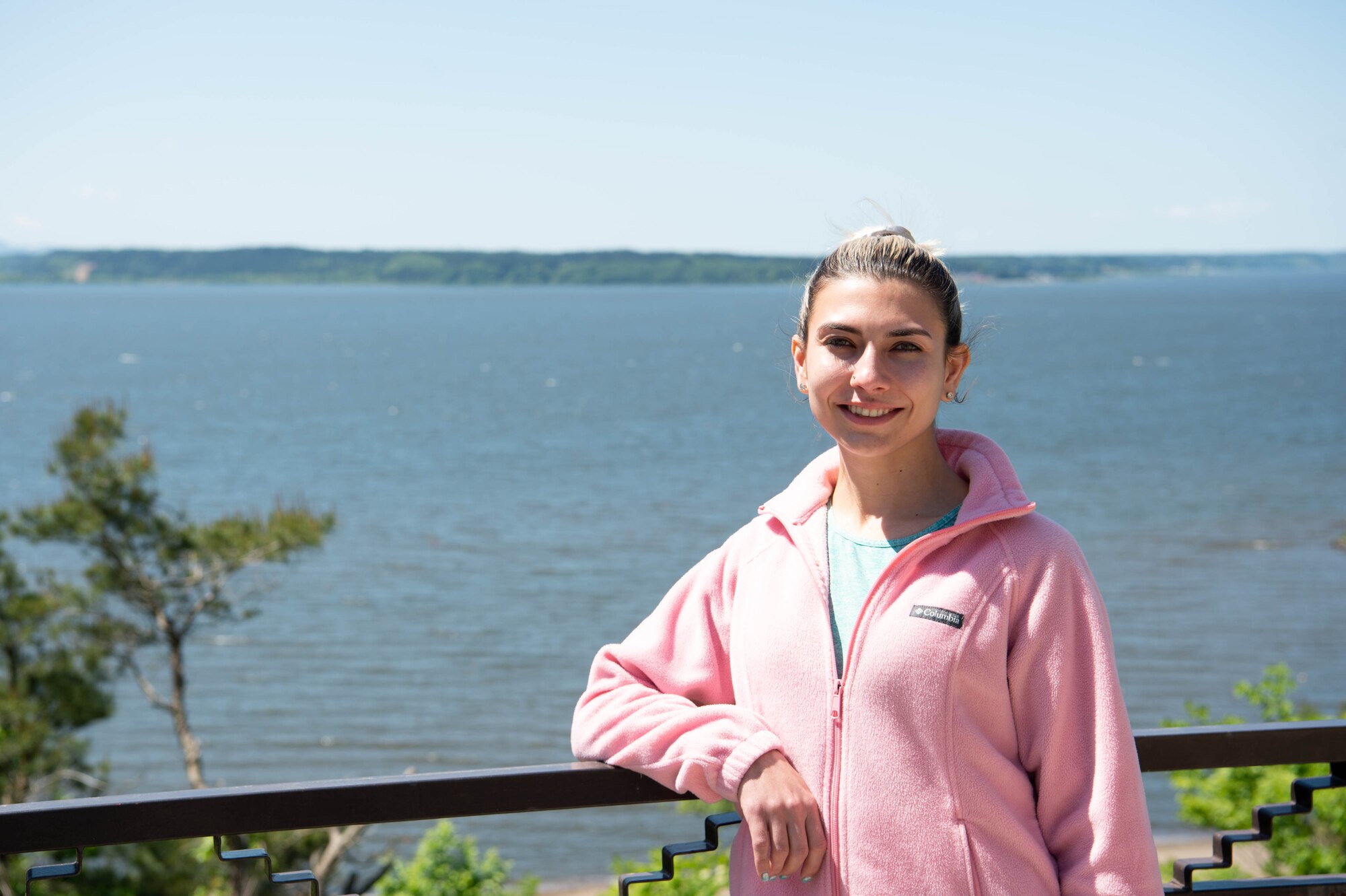 Military spouse poses in front of a lake for a portrait.