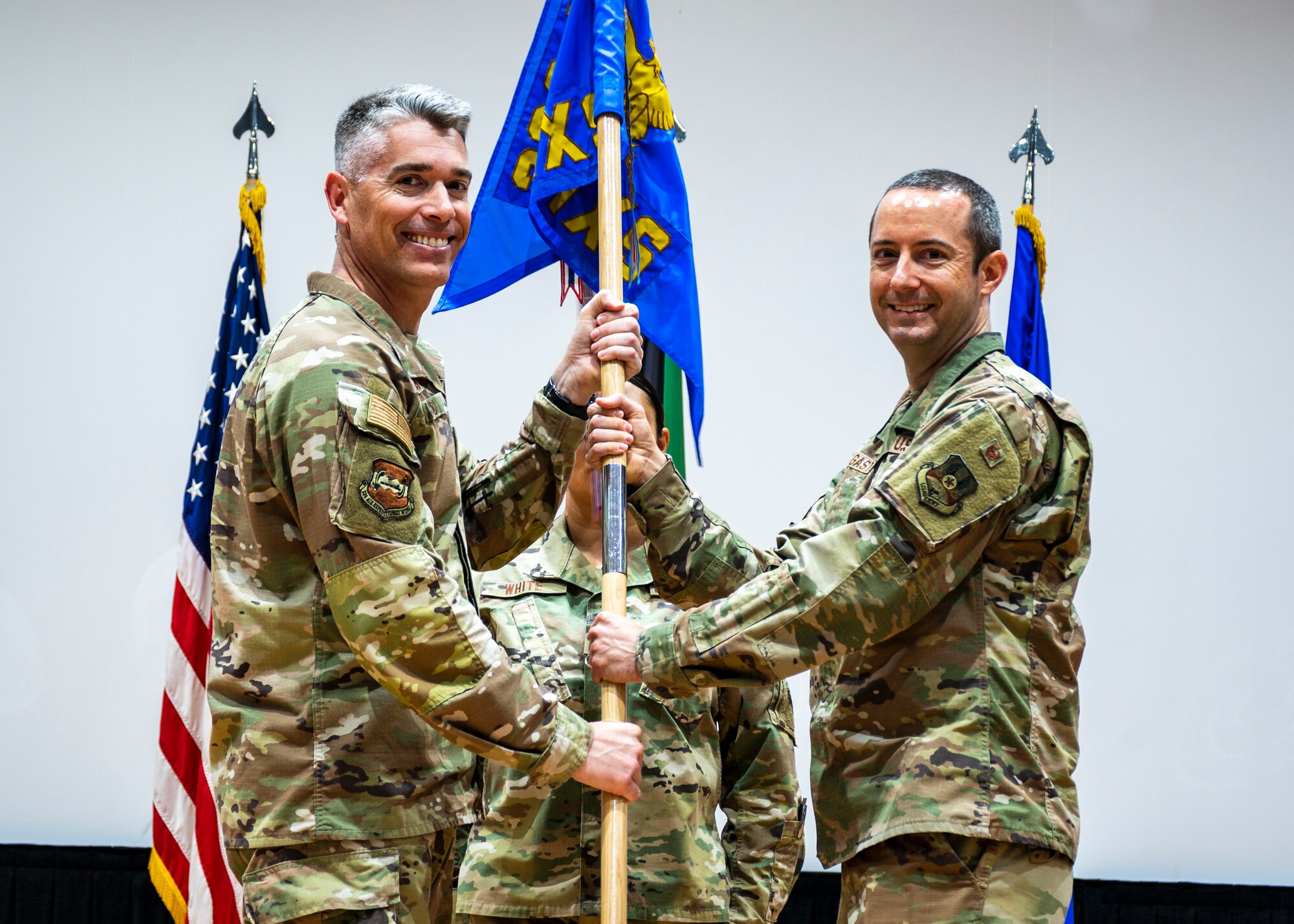 Col. George Buch, 386th Air Expeditionary Wing commander, passes the guidon to Maj. Edwin Gaston, incoming 386th EAMXS commander, during a change of command ceremony